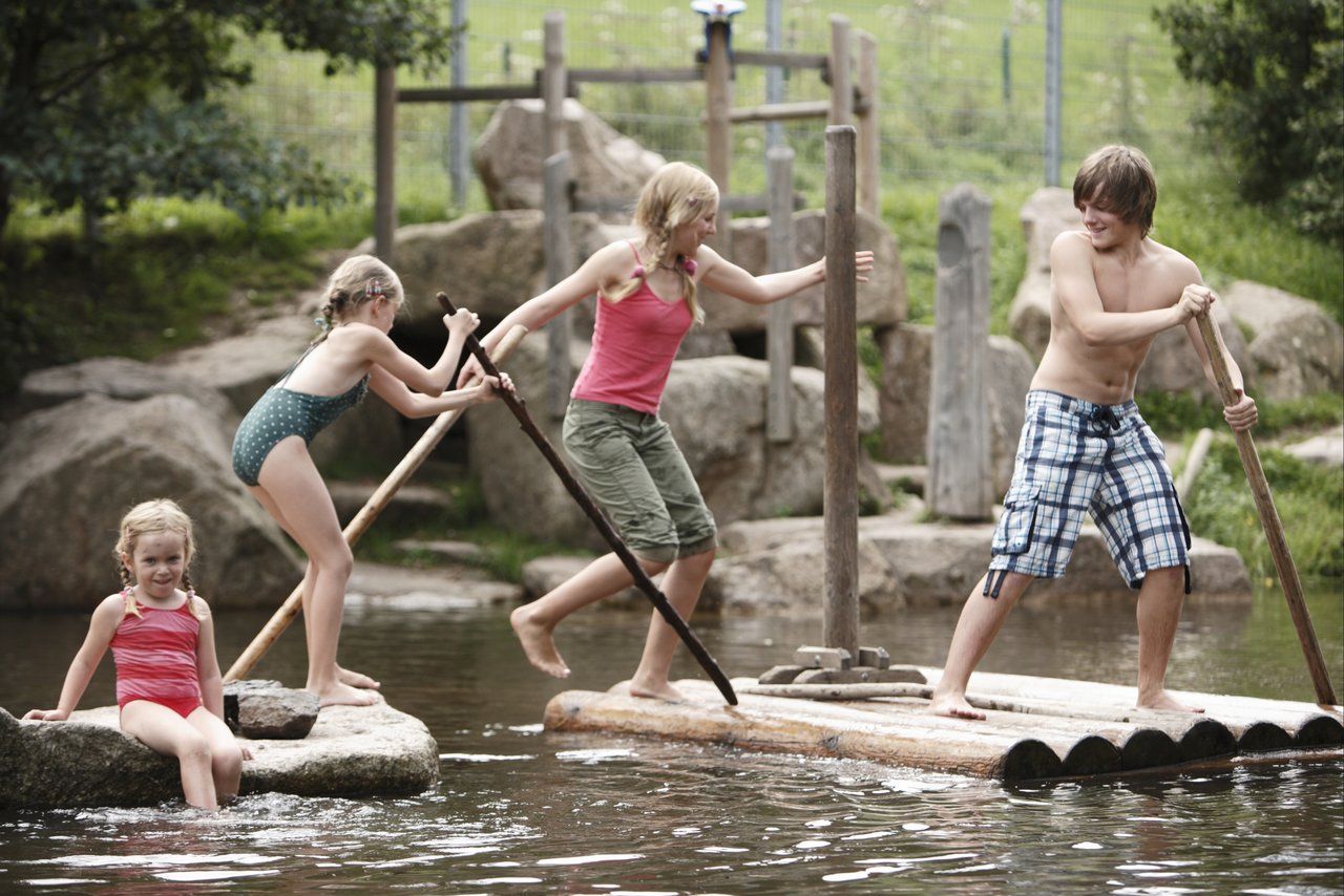 Spielende Kinder auf einem Floss im Teich
